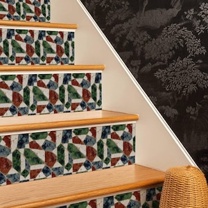 May include: A staircase featuring risers decorated with a geometric mosaic pattern in shades of red, green, and blue on a white background. The treads are made of light-colored wood with rounded edges, and the wall beside the stairs is black.