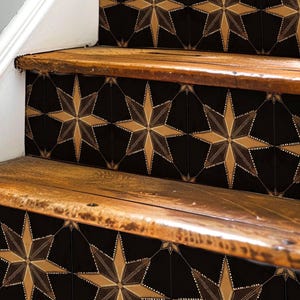May include: Close-up of wooden stairs with black and gold star-shaped tile decals. The tiles have a geometric pattern and are arranged in a repeating pattern.