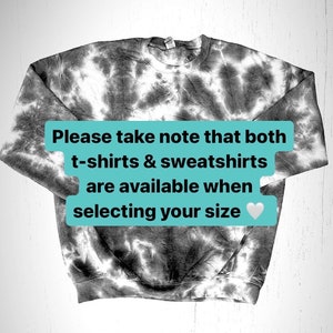 Pu&ograve; includere: Una felpa tie-dye bianco e nero con il testo "Si prega di notare che sia le t-shirt che le felpe sono disponibili al momento della selezione della taglia" in una casella turchese con un cuore bianco.