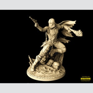 Puede incluir: Una figura impresa en 3D de color beige de un personaje de Star Wars, The Mandalorian, sosteniendo un bl&aacute;ster y un lanzallamas. El personaje est&aacute; de pie sobre una base rocosa con arena y dos cascos ca&iacute;dos.
