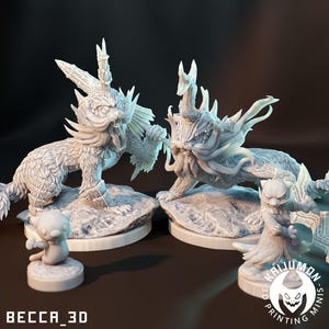 May include: A collection of detailed, light-colored fantasy creature figurines. Two large, dragon-like figures are posed on rocky bases, with smaller figures in front. The text "BECCA_3D" and "KAIJUMON PRINTING MINIS" are visible.