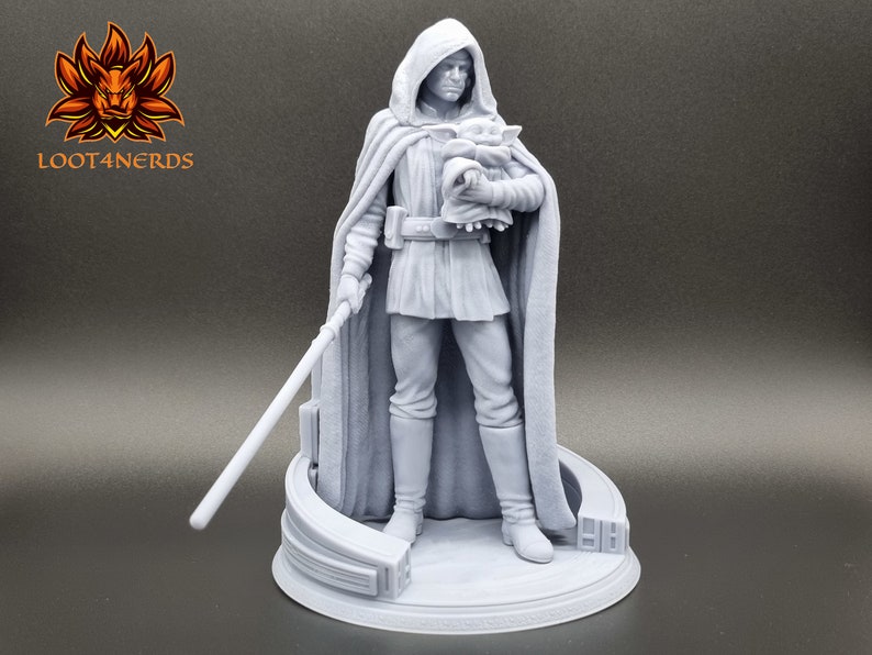 Puede incluir: Una figura impresa en 3D de color gris de un personaje de la franquicia Star Wars, sosteniendo una peque&ntilde;a figura en sus brazos. El personaje lleva una t&uacute;nica con capucha y sostiene un sable de luz. La figura est&aacute; de pie sobre una base circular.