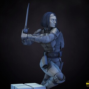以下が含まれることがあります： スターウォーズの女性キャラクターのグレーで詳細な3Dモデル。ヘルメットとアーマーを着用し、武器を持っています。キャラクターは戦闘姿勢で、プラットフォームにひざまずいています。画像の右下隅に「スターウォーズ」というテキストが表示されています。