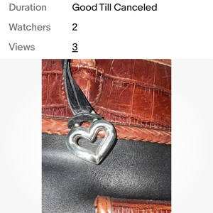 May include: A brown leather purse with a silver heart-shaped charm. The purse has a textured, crocodile-like pattern and a black strap. The image also shows the text "Sorry, this item did not sell."