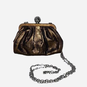 Pode incluir: Uma bolsa clutch bronze com uma al&ccedil;a de corrente prateada. A bolsa tem uma apar&ecirc;ncia texturizada e franzida e um fecho prateado decorativo. A corrente &eacute; um design de elos.