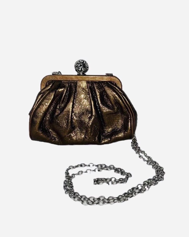 Pode incluir: Uma bolsa clutch bronze com uma al&ccedil;a de corrente prateada. A bolsa tem uma apar&ecirc;ncia texturizada e franzida e um fecho prateado decorativo. A corrente &eacute; um design de elos.