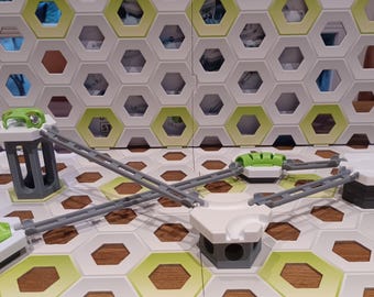Puede incluir: Un juego de recorrido de canicas blanco y verde con una base en forma de panal. El juego incluye una variedad de pistas, rampas y obstáculos. El juego está diseñado para desafiar a los jugadores a crear diferentes recorridos de canicas.