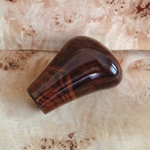 May include: A dark brown wooden gear shift knob with a glossy finish.