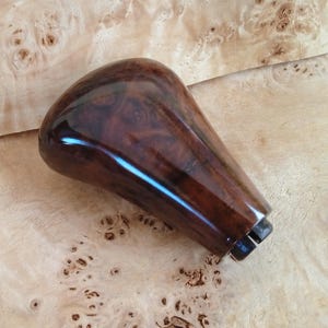 May include: A dark brown wooden gear shift knob with a glossy finish.