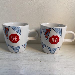 Set aus zwei Douwe Egberts-Bechern, Flaggen,