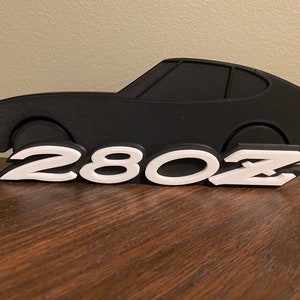 May include: A black 3D printed silhouette of a Datsun 280Z with the number "280Z" printed in white below the car.