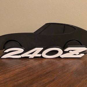 May include: A black 3D printed silhouette of a classic sports car with the text "240Z" in white lettering.