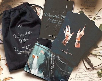 May include: A black drawstring pouch with the text West of the Moon, a black guidebook with the same title, and a deck of cards featuring illustrations of hands with celestial symbols, all displayed on a surface with handwritten script.