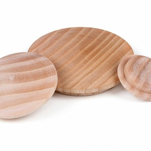 May include: Three wooden circles of varying sizes, all with a grooved texture. The circles are light brown in colour and appear to be unfinished.