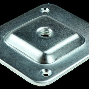 May include: A silver metal square plate with four holes and a threaded centre hole.