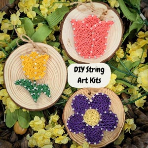 May include: Three DIY string art kits featuring flower designs. The kits include a wooden base, string, and nails. The flowers are yellow, pink, and purple.