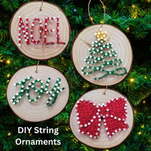 May include: Four DIY string art Christmas ornaments on wood slices. The ornaments are a red bow, a green Christmas tree, the word "Joy" in green, and the word "Noel" in red.