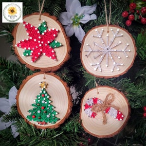 May include: Four wooden Christmas ornaments with string art designs. The ornaments feature a poinsettia, snowflake, Christmas tree, and candy cane. Each ornament is a wood slice with a natural bark edge and a twine hanger.