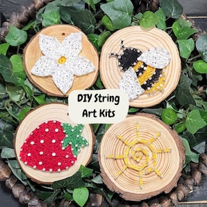 May include: Four DIY string art kits on wooden rounds. The designs are a white flower, a yellow and black bee, a red strawberry, and a yellow sun.