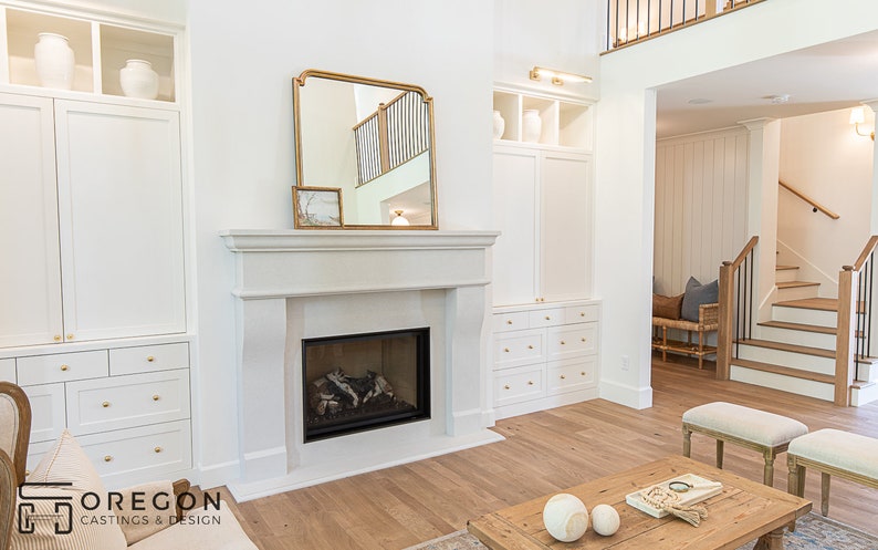 May include: A white fireplace with a gas log fire in a living room with white built-in cabinets and a large mirror above the fireplace.