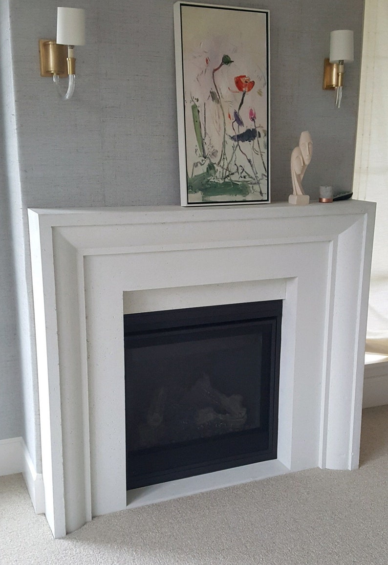 May include: White fireplace surround with a black gas fireplace insert. The fireplace is decorated with a framed painting of flowers and a small sculpture.