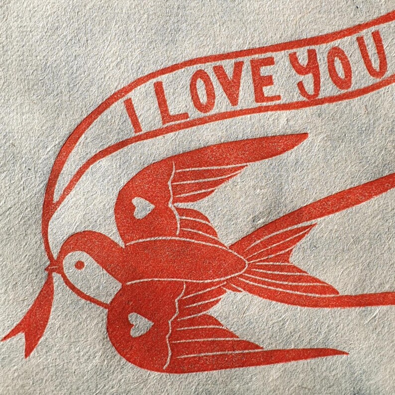 Op de afbeelding: Een illustratie van twee rode vogels die vliegen met een banner waarop "I LOVE YOU" staat.