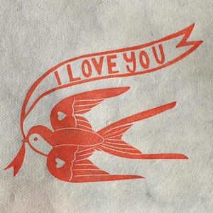 Op de afbeelding: Rode illustratie van twee vogels met harten op hun vleugels, die vliegen met een banner waarop "I LOVE YOU" staat.