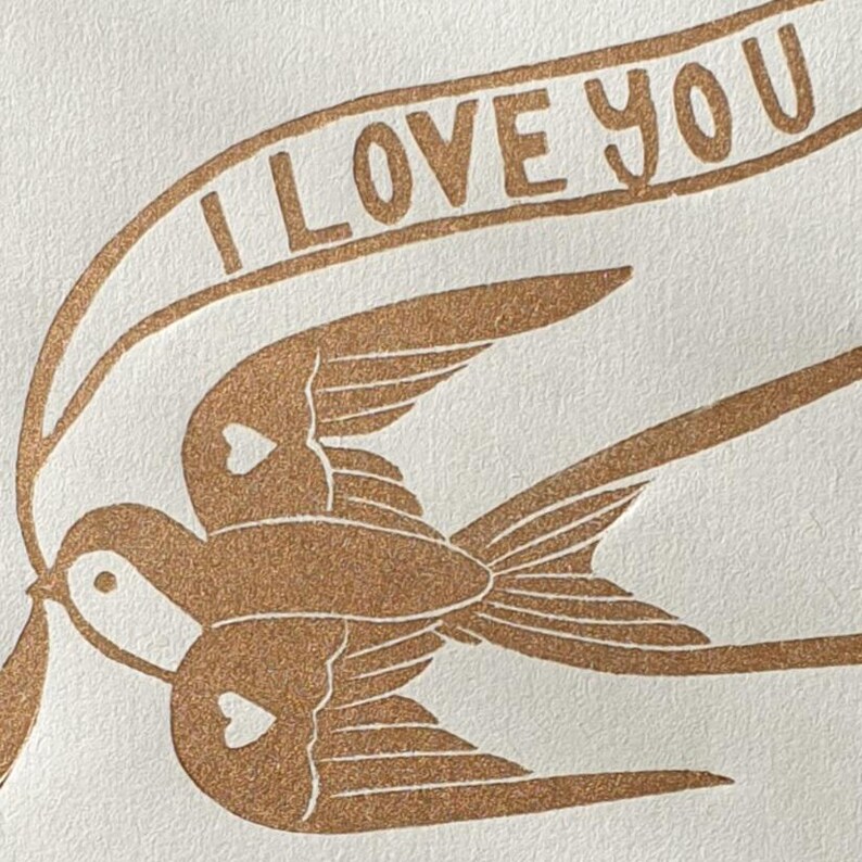 Op de afbeelding: Twee bruine vogels met harten op hun borst vliegen samen met een banner waarop "I LOVE YOU" staat.