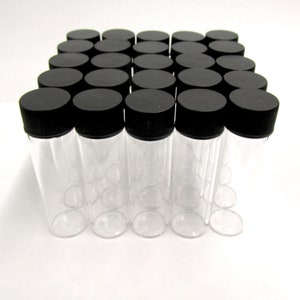 Op de afbeelding: Een verzameling heldere glazen flesjes met zwarte schroefdoppen. De cilindrische flesjes zijn in een rasterpatroon gerangschikt, wat hun uniforme ontwerp benadrukt. De doppen zorgen voor een veilige afsluiting, geschikt voor diverse toepassingen. (ongeveer 10 cm hoog)