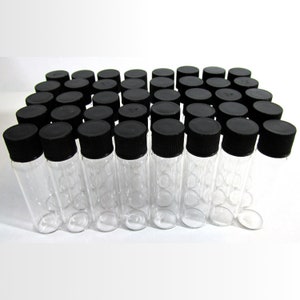 Peut inclure: Un groupe de 36 flacons en verre transparent avec des bouchons à vis noirs. Les flacons sont disposés en un motif rectangulaire.
