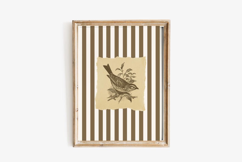 Op de afbeelding: Een ingelijst kunstwerk met een gedetailleerde illustratie van een vogel op een tak. De vogel staat tegen een gescheurd, bruin papier, dat gecentreerd is op een gestreepte achtergrond van bruine en cr&egrave;mekleurige verticale lijnen. De lijst heeft een lichte houtkleur.