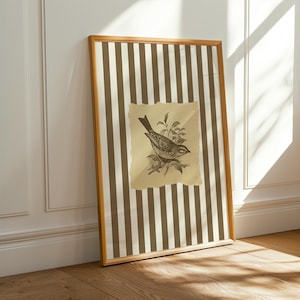 Op de afbeelding: Een ingelijst kunstwerk met een vintage vogelillustratie. Het kunstwerk heeft een gestreepte achtergrond van bruine en cr&egrave;mekleurige verticale lijnen. De vogelillustratie staat op een gescheurd, verouderd papier. De lijst is lichtbruin.