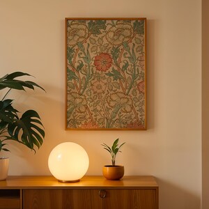 May include: A white glass globe lamp with a wooden base sits on a wooden table next to a potted plant. A framed floral print hangs on the wall behind the lamp.
