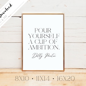May include: A gold-framed printable quote with white background and black text. The quote reads "Pour yourself a cup of ambition." and is attributed to Dolly Parton. The sizes 8x10, 11x14, and 16x20 are listed below the quote.