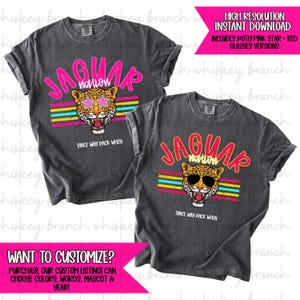 May include: Two charcoal gray t-shirts with a jaguar graphic. The graphic includes the text "JAGUAR nation" above a jaguar head wearing sunglasses, with the text "SINCE WAY BACK WHEN" below. The design features pink, yellow, and blue stripes.