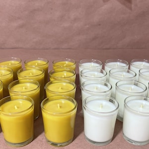 Puede incluir: Una colección de 20 pequeños tarros de velas de vidrio. Diez tarros están llenos de velas de cera de abeja amarilla y diez tarros están llenos de velas blancas.