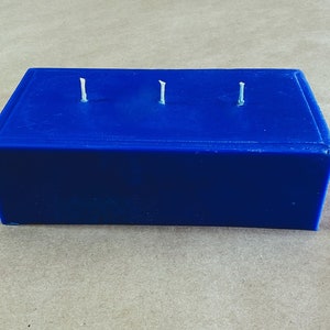 Puede incluir: Una vela azul rectangular con tres mechas.