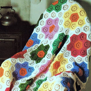 May include: A colorful crochet blanket with a white background and a variety of bright colors, including red, orange, yellow, green, blue, and pink. The blanket is made up of a repeating pattern of hexagons.