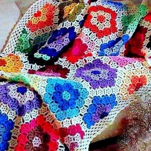 Puede incluir: Una manta de ganchillo colorida con un patrón floral. La manta está hecha de cuadrados en varios colores, incluyendo rojo, azul, verde, amarillo y morado.