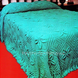 May include: A teal crochet bedspread with a floral pattern and fringe trim. The bedspread is on a bed with a teal pillow.