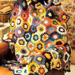 Può includere: Una coperta all'uncinetto colorata con un motivo floreale in tonalità di giallo, arancione, rosso, blu, verde e marrone.