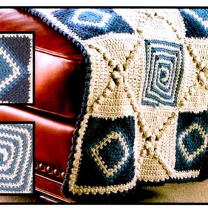 May include: A crocheted throw blanket with a geometric pattern in shades of blue and white. The blanket is draped over a brown leather armchair.