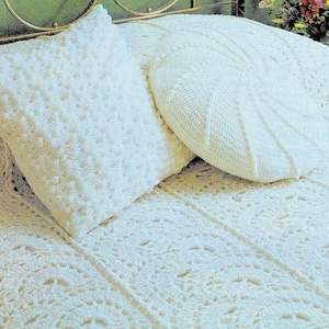 May include: A white crocheted bedspread with a white crocheted pillow and a white crocheted round pillow. The bedspread has a delicate lace pattern.
