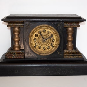 May include: Antique black mantel clock with gold accents and a Roman numeral clock face.