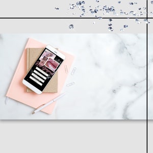 May include: A white smartphone displaying a mobile website with a black background and pink and white text. The text reads "Hire Gorgeous!" and includes a list of services: "Lash Now", "Lash Lift", "Lash Extensions", "Brow Wax", "Brow Tint", "Microblading", "Waxing". The phone is on top of two notebooks, one pink and one gold.
