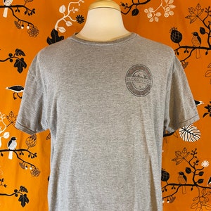 May include: A gray t-shirt with a vintage-style logo that says "Jackson Hole" in a circle with a mountain scene inside. The logo is printed on the front of the shirt.