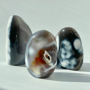 Könnte beinhalten: Drei Achat-Steine, jeder mit einem einzigartigen Muster aus Grau, Weiß und Braun. Der mittlere Stein hat eine rotbraune Mitte.