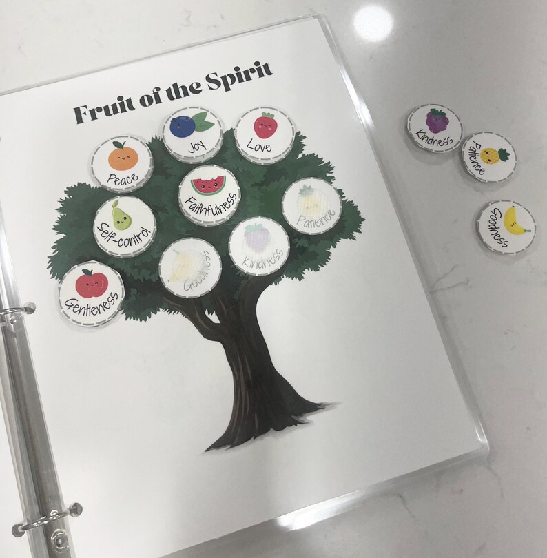 K&ouml;nnte beinhalten: Ein wei&szlig;es Blatt Papier mit einer schwarzen und gr&uuml;nen Baumillustration. Der Baum hat neun runde, fruchtf&ouml;rmige Aufkleber mit W&ouml;rtern wie "Liebe", "Freude", "Frieden" und "Treue". Die W&ouml;rter sind die "Frucht des Geistes" aus der Bibel.