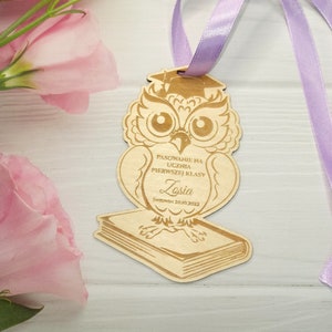 May include: Wooden owl figurine with a graduation cap, holding a book. The owl is decorated with a  "PASOWANIE NA UCZNIA PIERWSZEJ KLASY" inscription and the name "Zosia" with the date "5WRZEDNIA 20.10.2022".