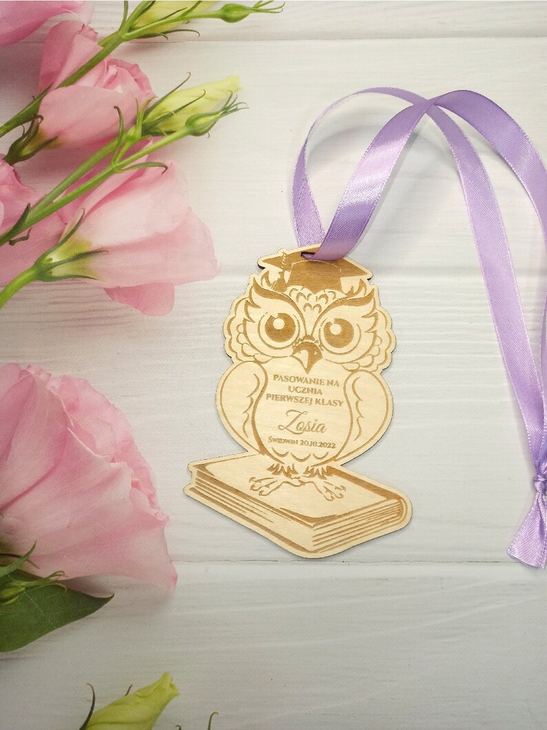 May include: Wooden owl figurine with a graduation cap, holding a book. The owl is decorated with the text "Pasowanie na ucznia pierwszej klasy" and the name "Zosia" with the date "01.06.2022".